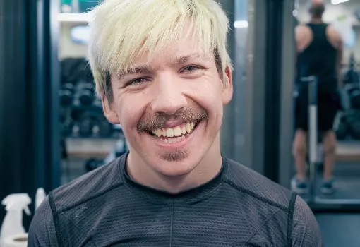 Man with blonde hair smiling in a gym.