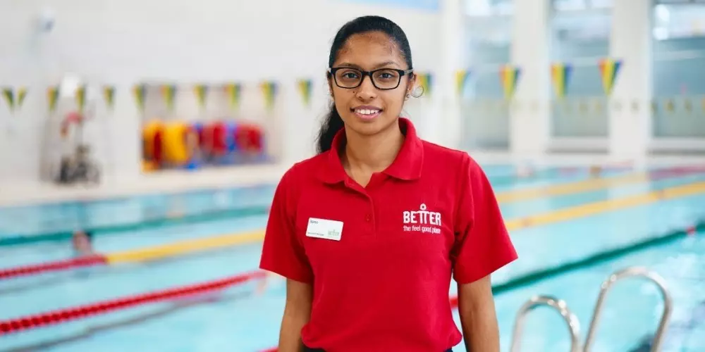 Swimming pool staff member standing beside an indoor pool.
