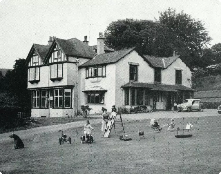 Vintage photo of a large house with children playing outside.