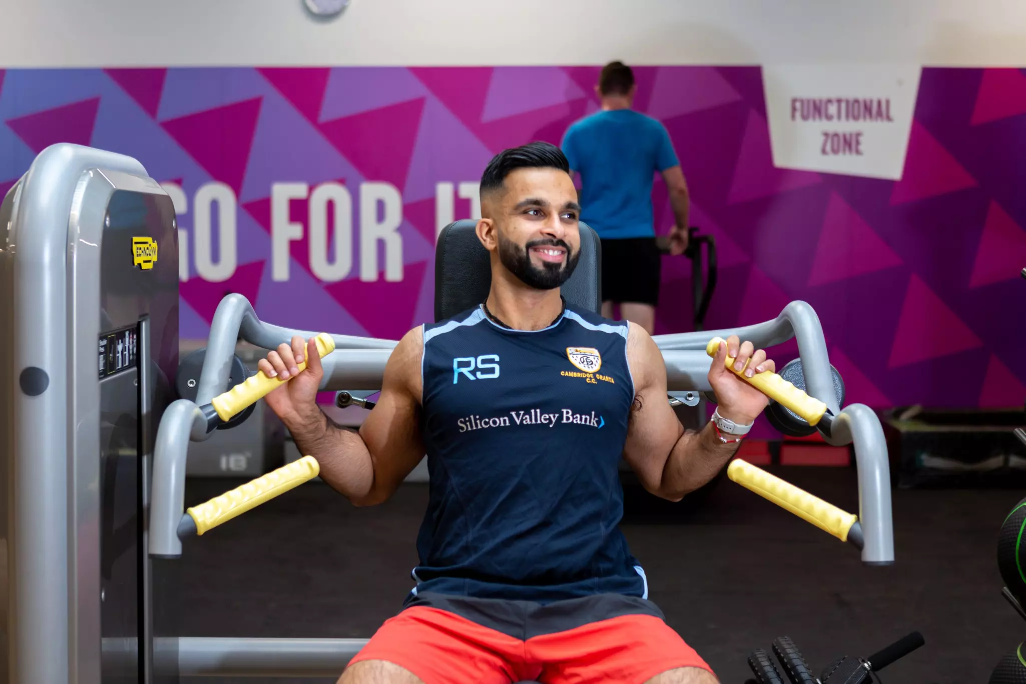 Man smiling while using shoulder press machine.