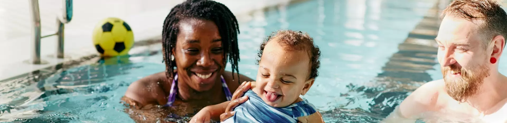 Family of four smiling together in a swimming pool.