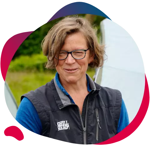 Smiling woman wearing glasses and an outdoor vest.