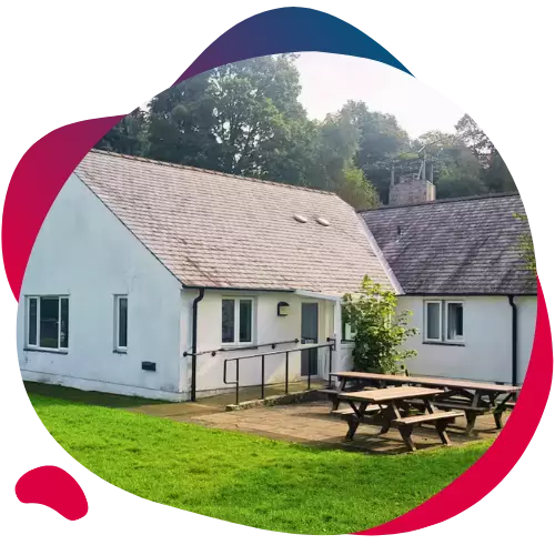Group of children and adults paddling a canoe on a calm lake with hills in the background.