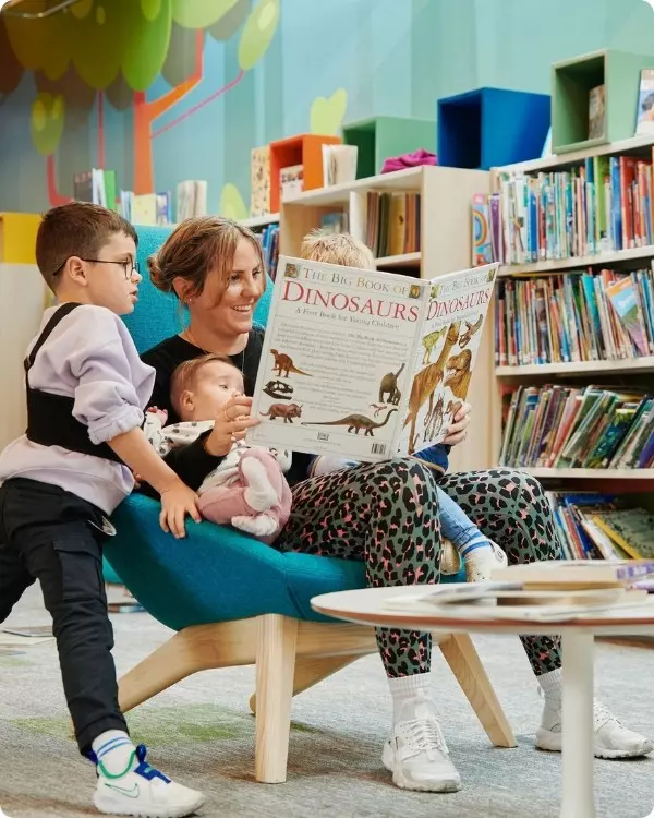 Mum at the library reading book to two kids.