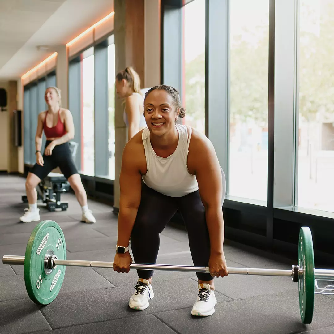 Woman lifting a barbell in a gym.