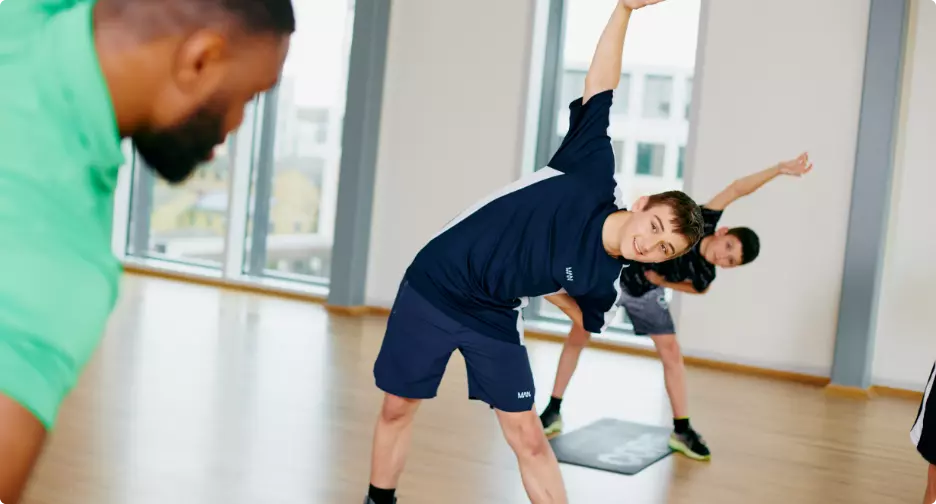 Instructor leading a stretching exercise in a studio.