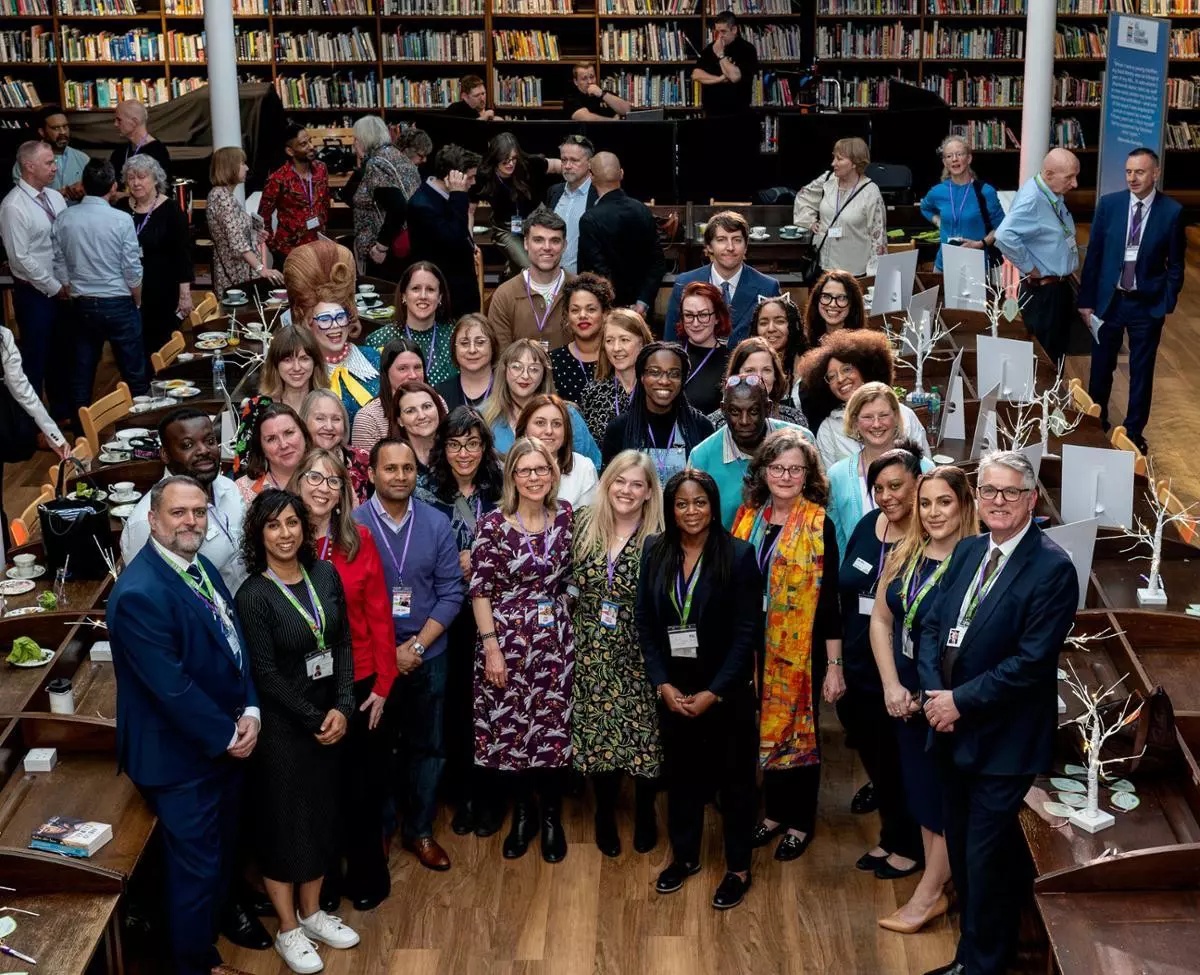  A large group of people are gathered in a library room.
