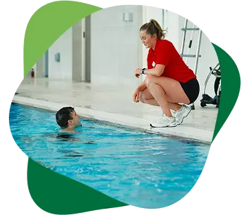 Swimming instructor talking to a swimmer at the edge of an indoor pool.
