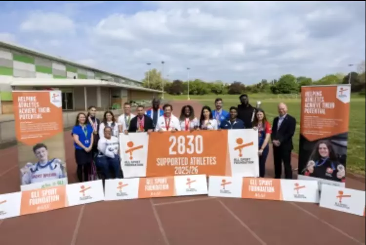 Group of athletes and staff on track with a banner showing 2,830 supported athletes.