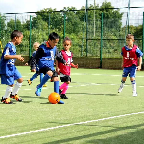 Children playing football on a school sports pitch.