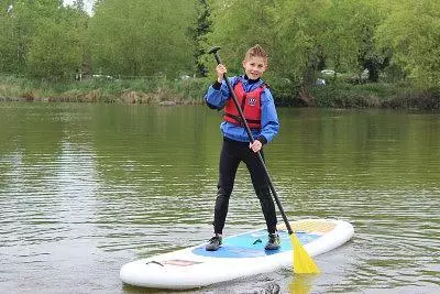 Child paddleboarding on a lake.