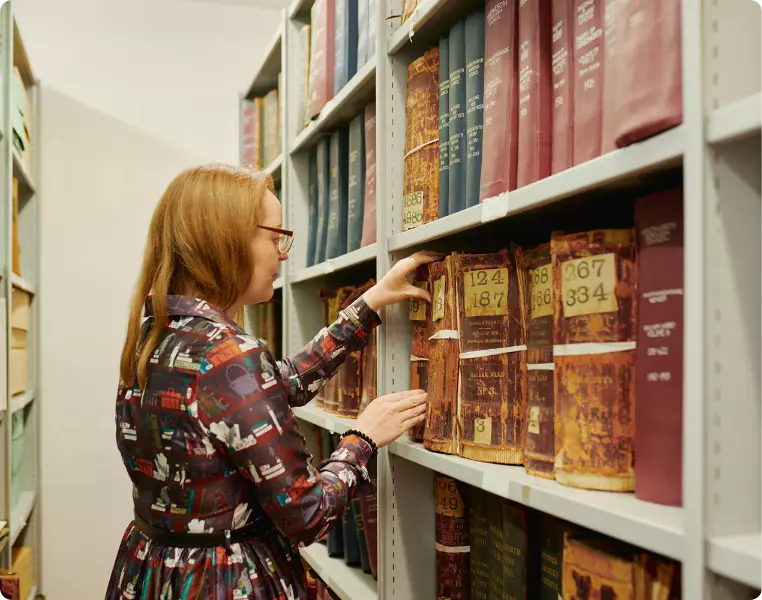 Woman browsing books in a library aisle.