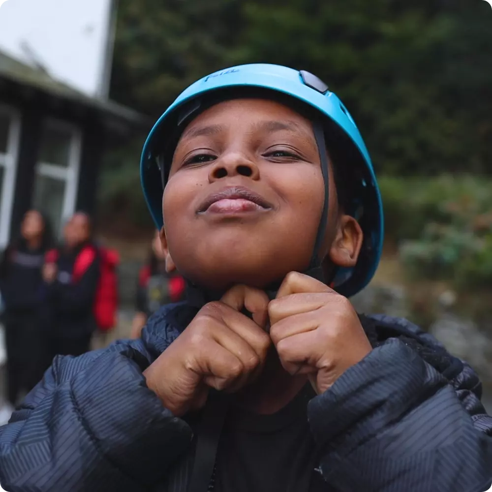 Child putting on helmet before outdoor activity at Ghyll Head.