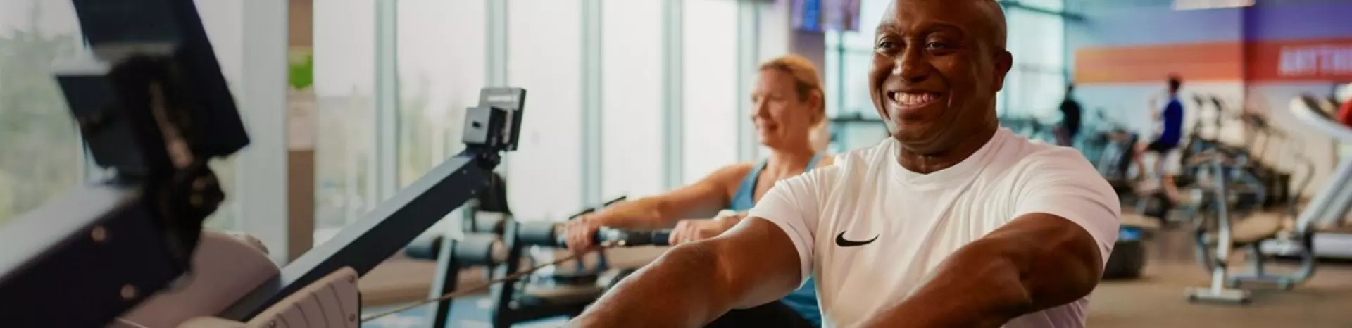 Man smiling in a gym while rowing.