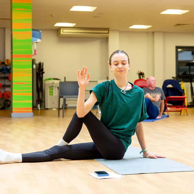 Women in Yoga class performing back stretch.