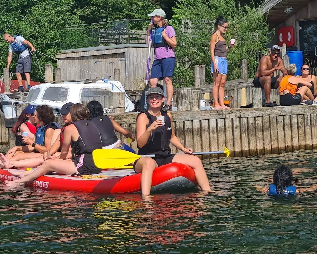  Woman sat on a paddleboard enjoying a refreshing drink in the sun