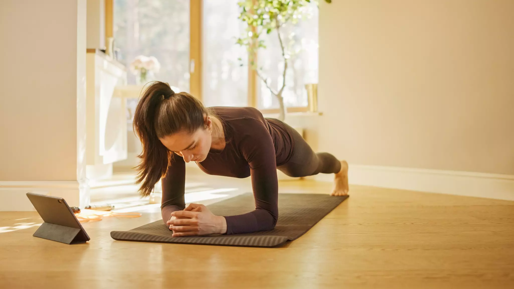 Woman doing plank on the mat in front of laptop.