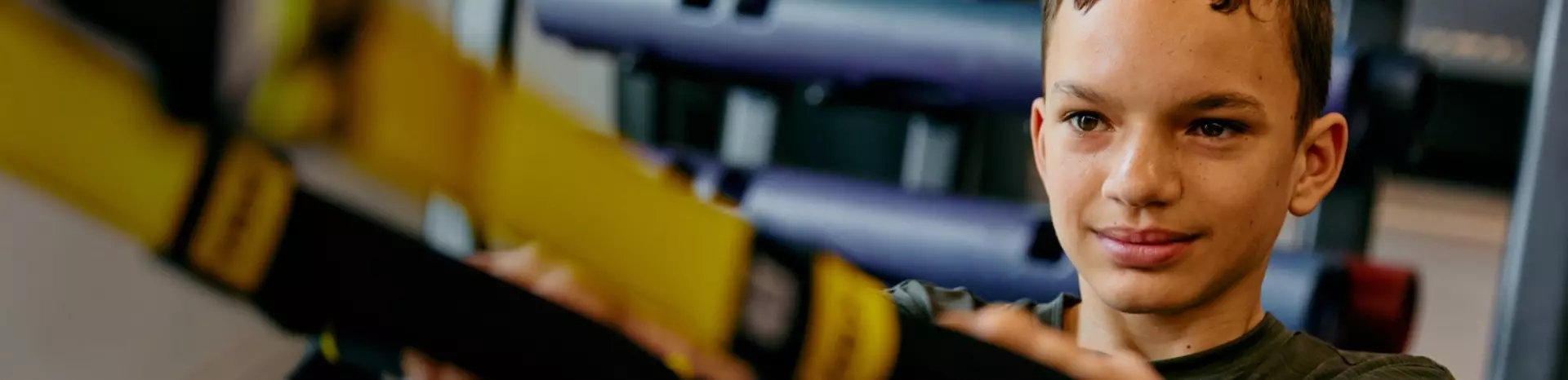 Boy using TRX in the gym.
