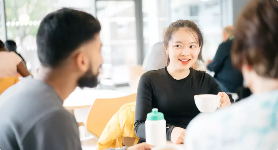 Three friends chatting over coffee in a café.