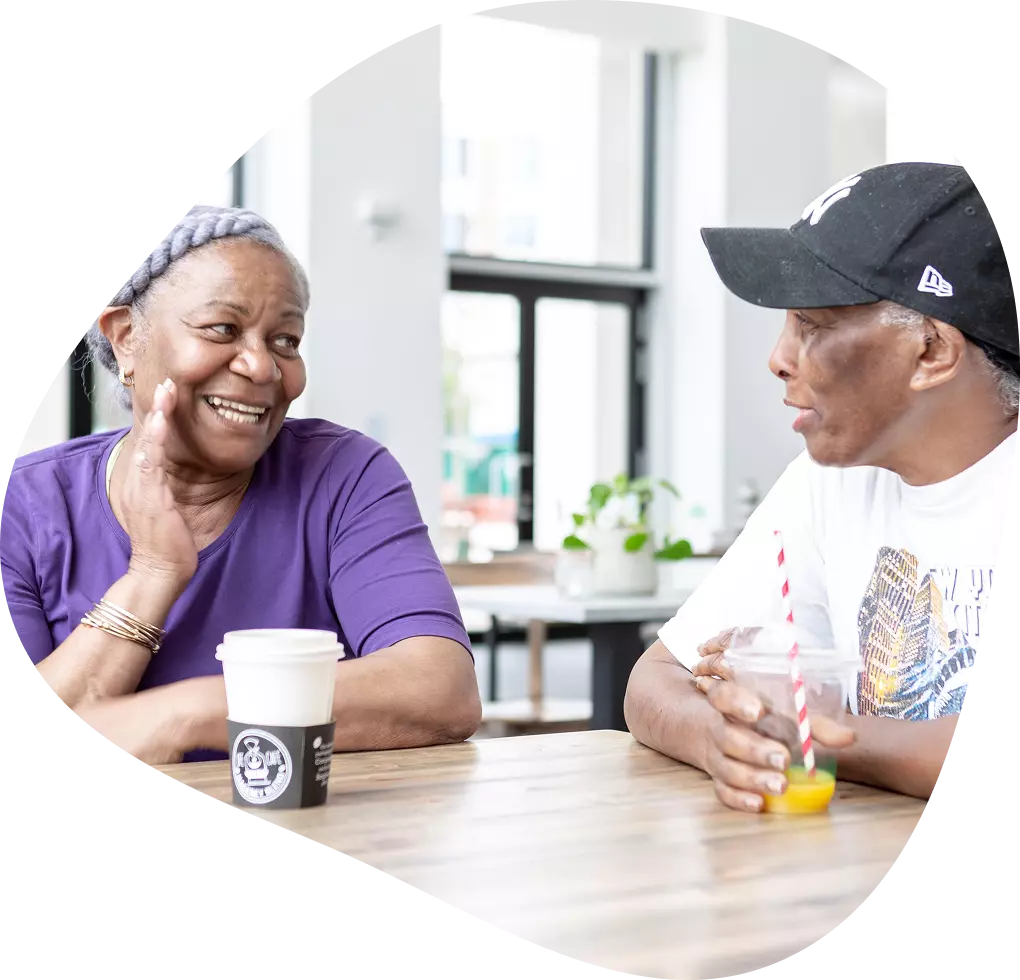 Two older adults chatting over coffee at a table.