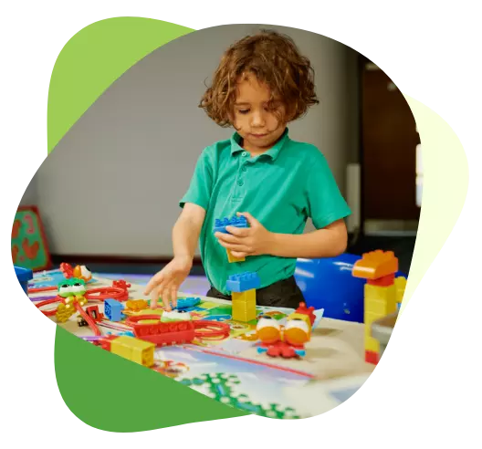 Young child playing with colorful building blocks at a table during a creative learning activity.