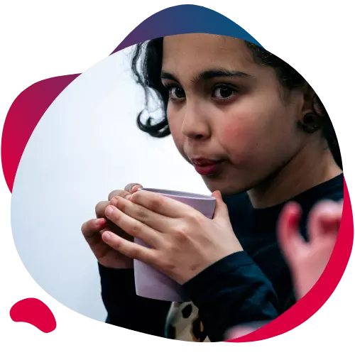 Child sipping from a cup while looking toward the camera.