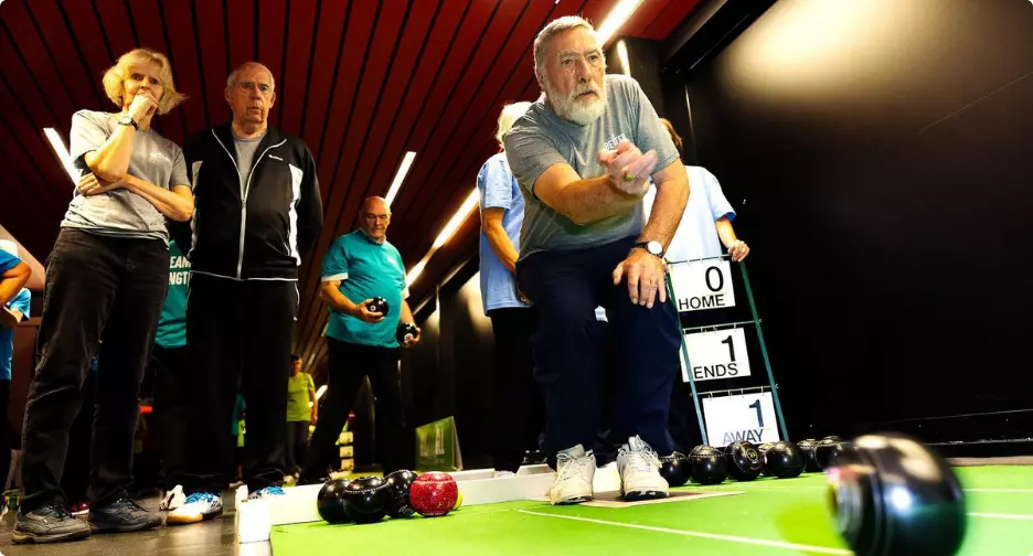Older adults playing indoor bowls.