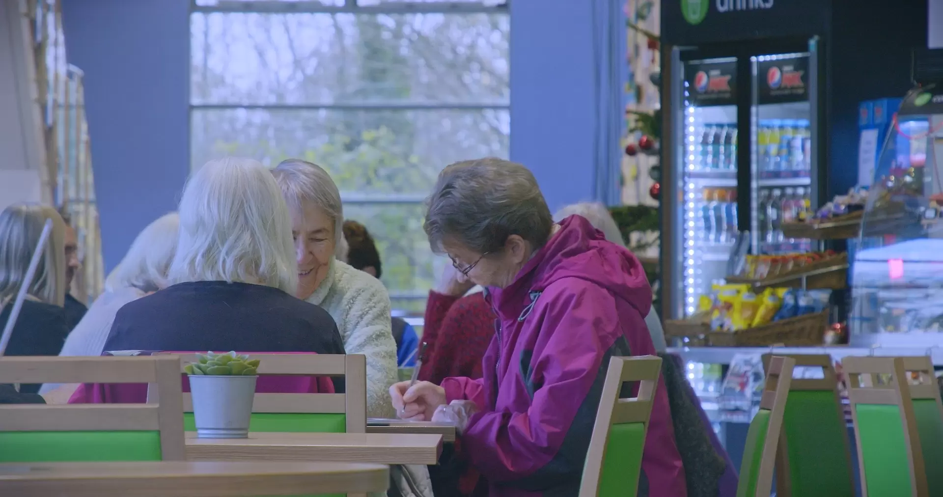 Two older adults chatting over coffee at a table.