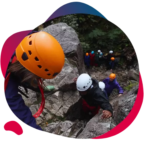 Group of children wearing helmets climbing through rocky terrain.