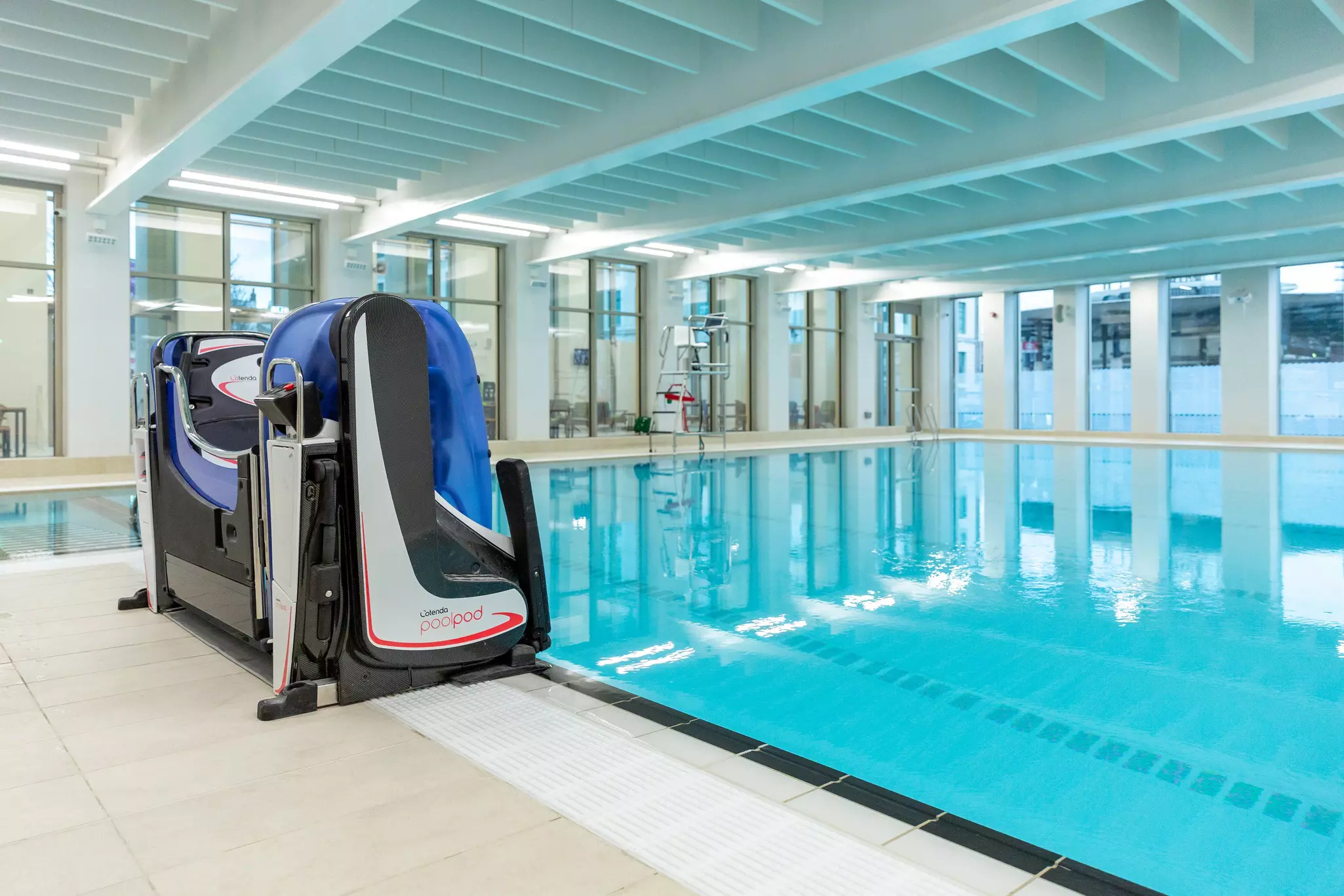 Pool hoist machine next to an indoor swimming pool.