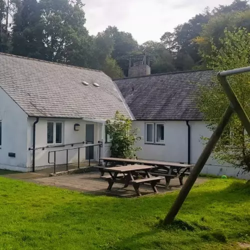 Single-storey white building with picnic benches outside.