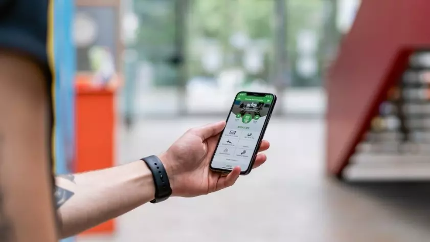 Person holding a smartphone displaying a fitness app outdoors.