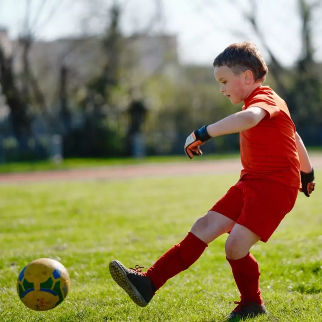 Boy kicking football ball.