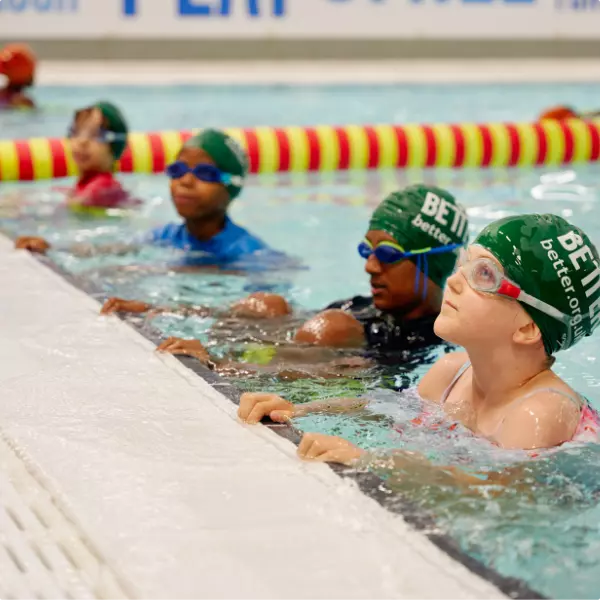 Children wearing swim caps during a school swimming lesson.