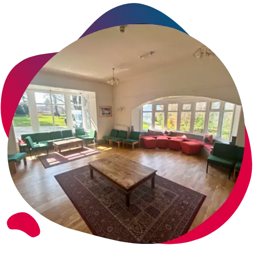 Spacious lounge with large windows, wooden floors, and seating areas.