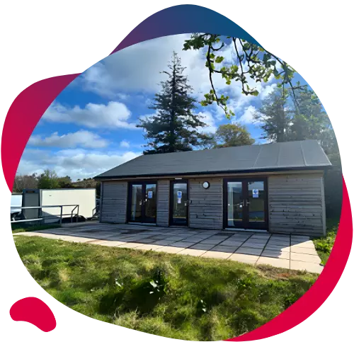 Modern wooden lodge with large windows set on a grassy area.