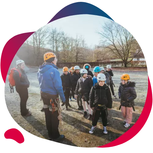 Group of children wearing helmets listening to an outdoor instructor.