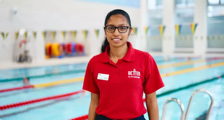 Lifeguard standing by an indoor swimming pool.