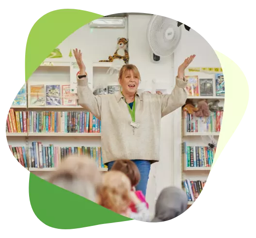 Woman leading a lively storytelling session for children in a colorful library setting.