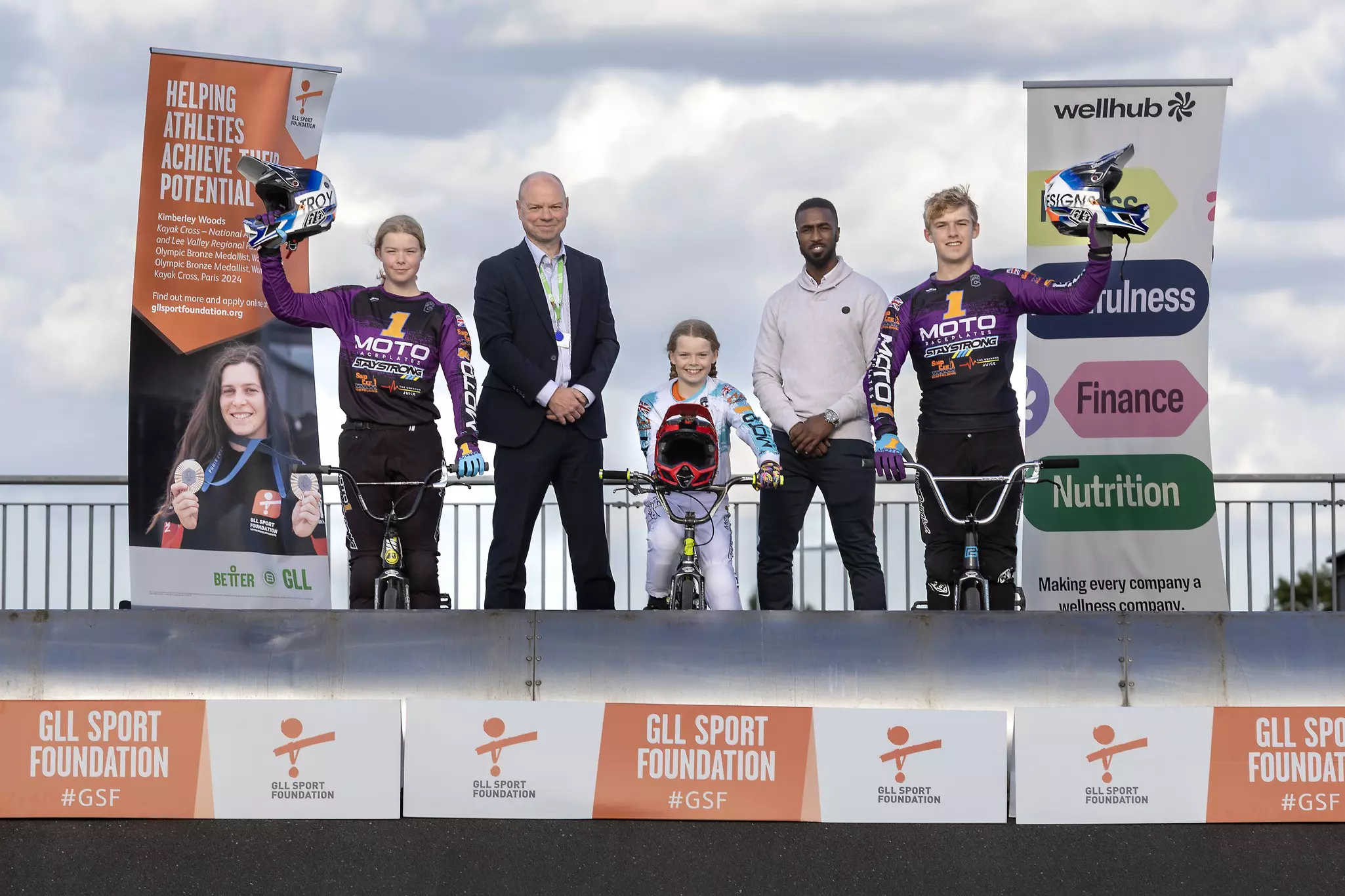 Three cyclists and two adults on a podium.