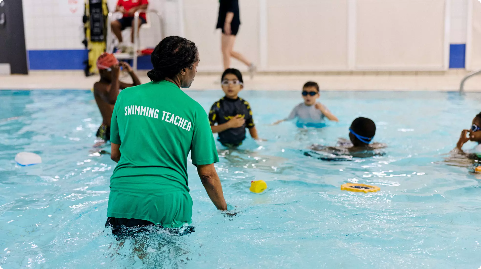 Swimming instructor leading a group of children in an indoor pool.