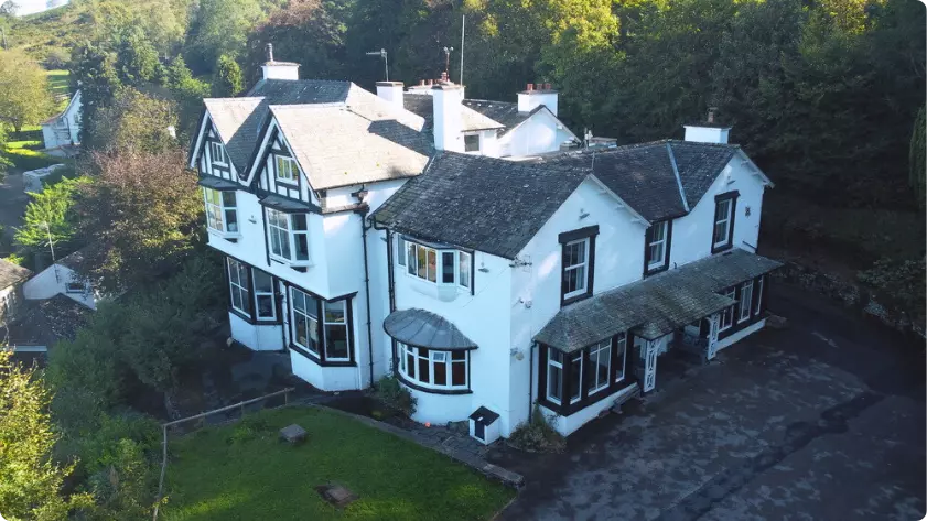Aerial view of a large white house surrounded by trees.