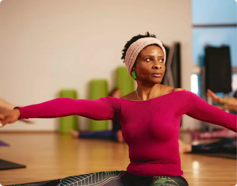 Woman stretching with arms out in a fitness class.