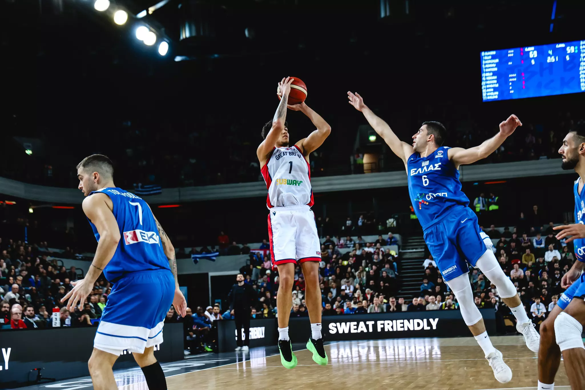 Basketball player in white jersey taking a jump shot while defended by players in blue jerseys.