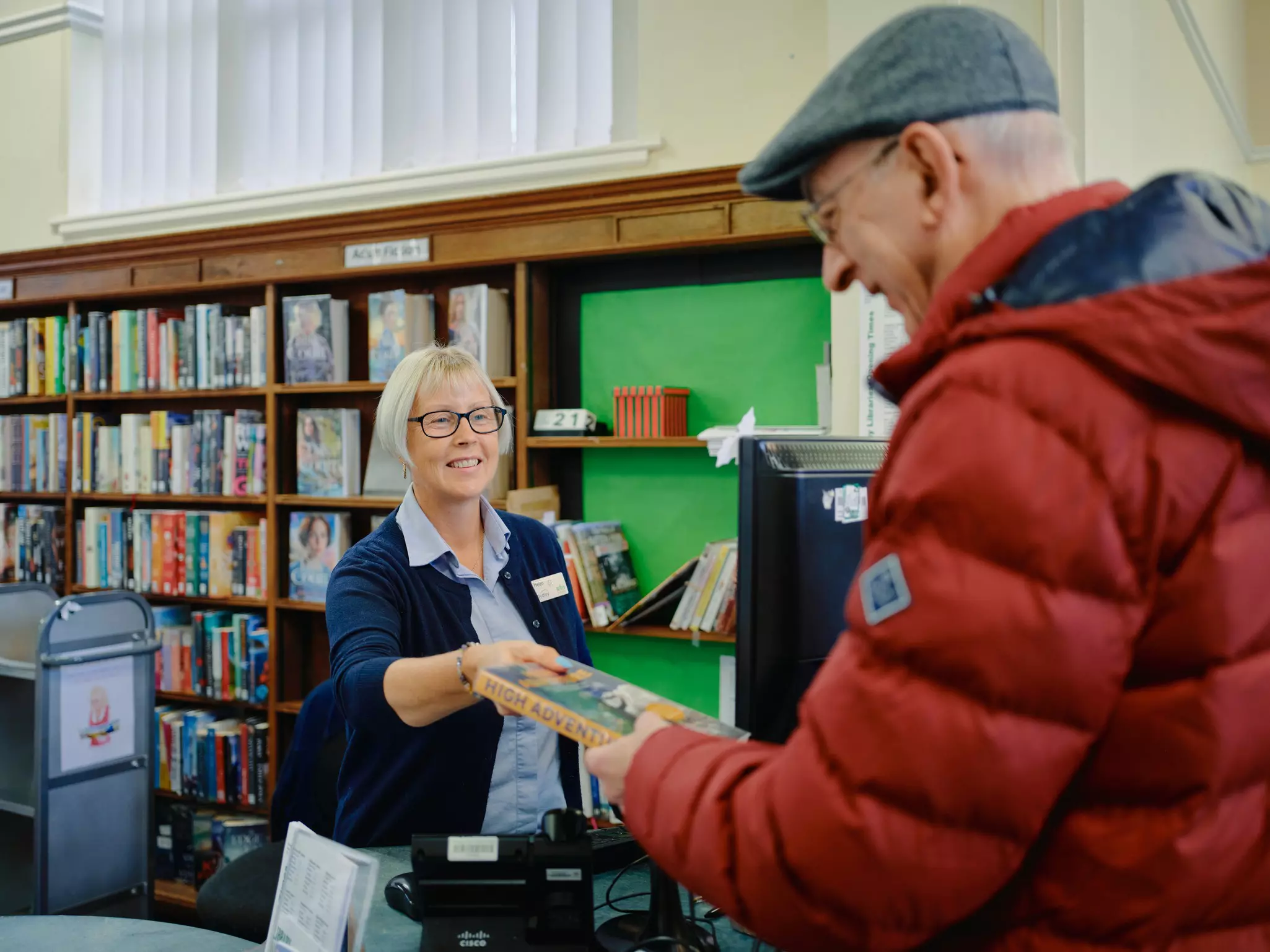 Librarian handing man a book in a library