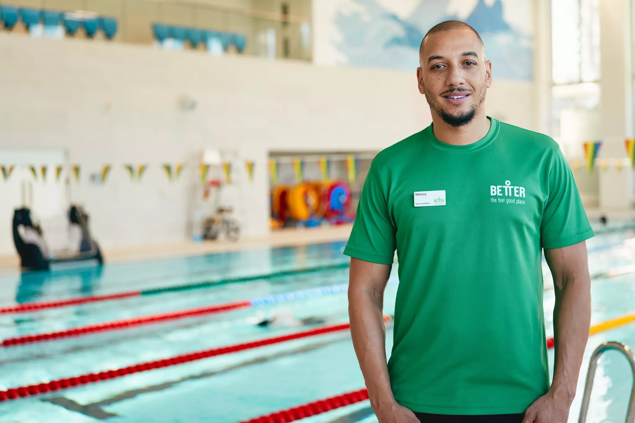 Man standing in front of the pool in green top.
