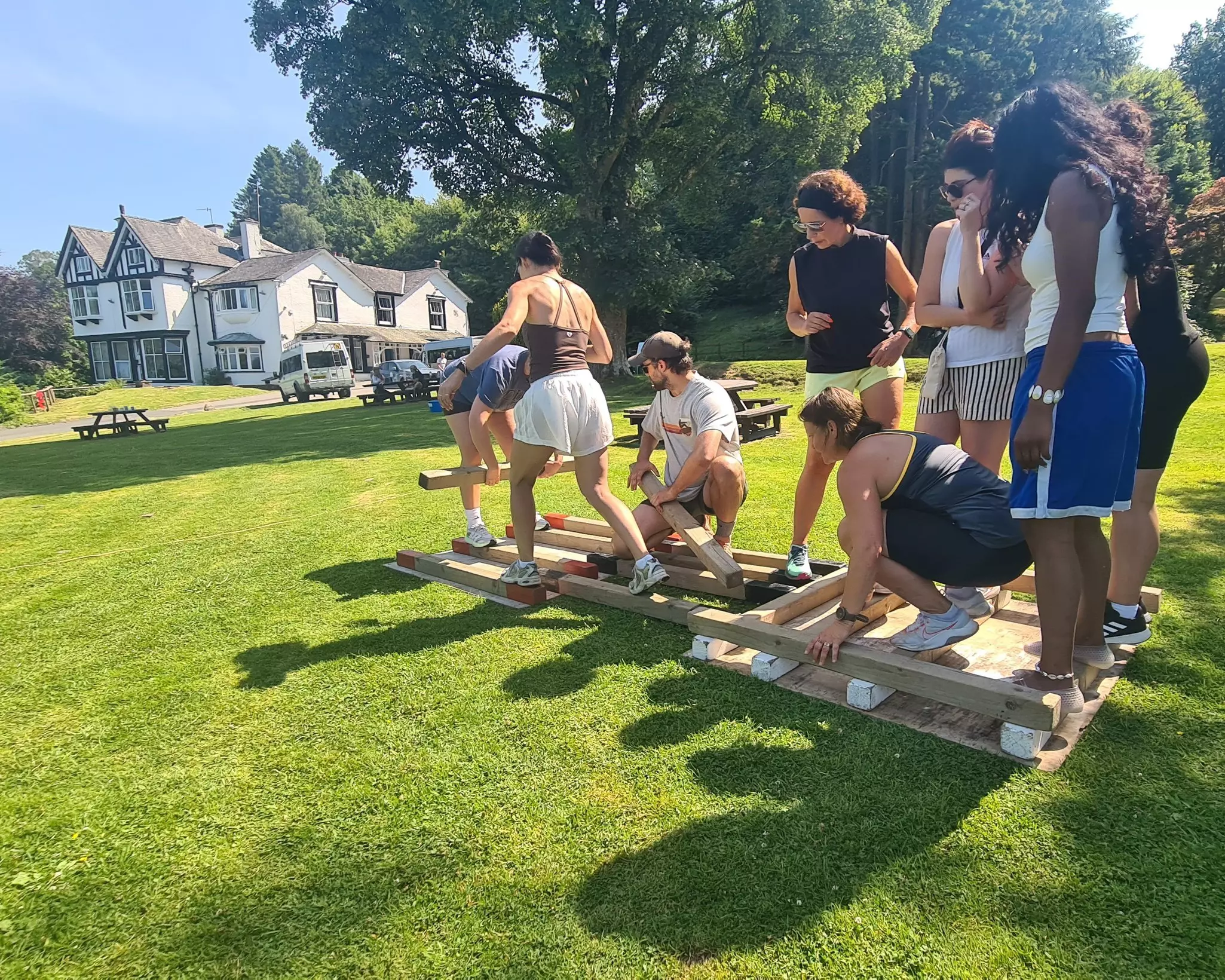Team playing a teambuilding game with planks of wood on the lawn