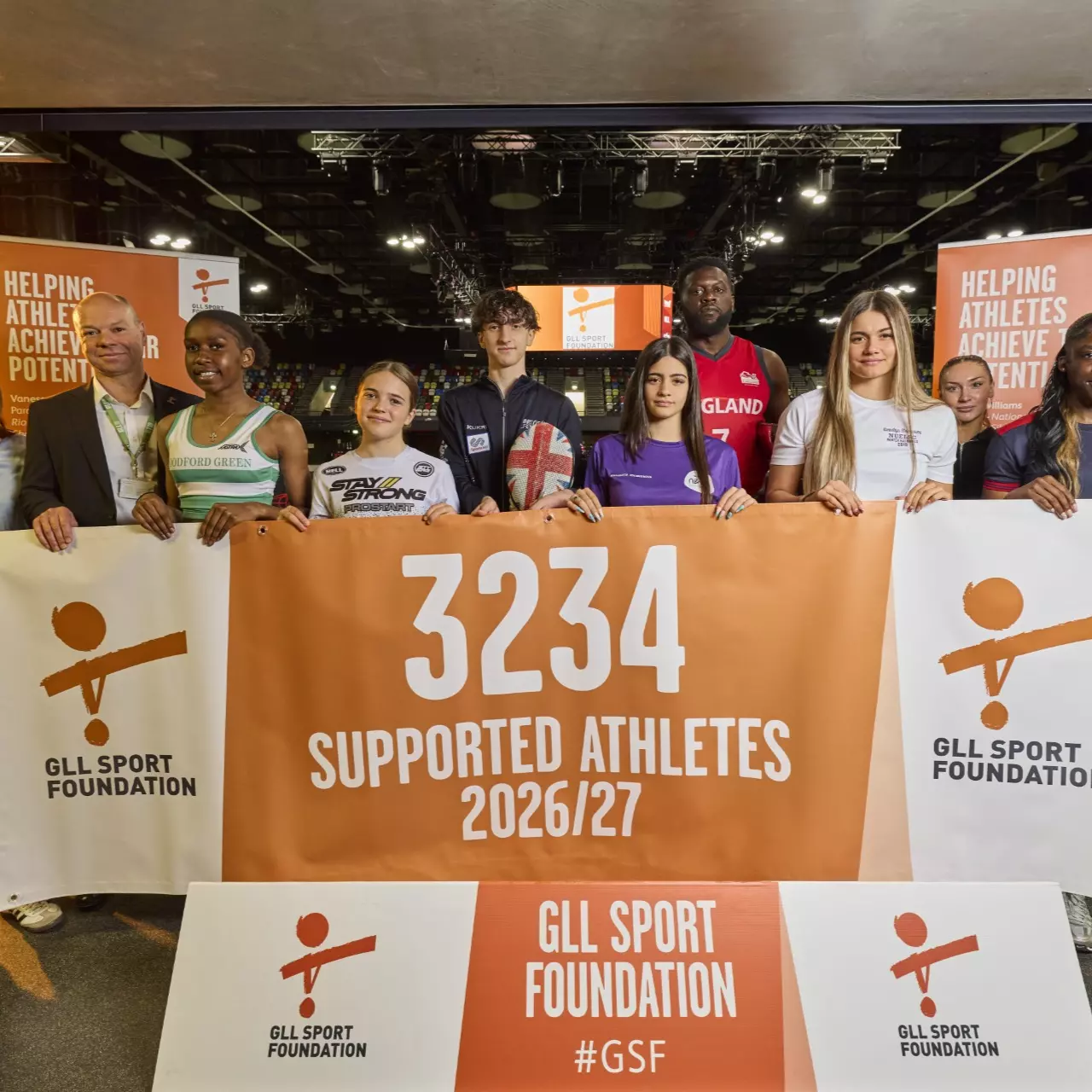 Group of people holding a banner showing 3234 supported athletes 2026/27.