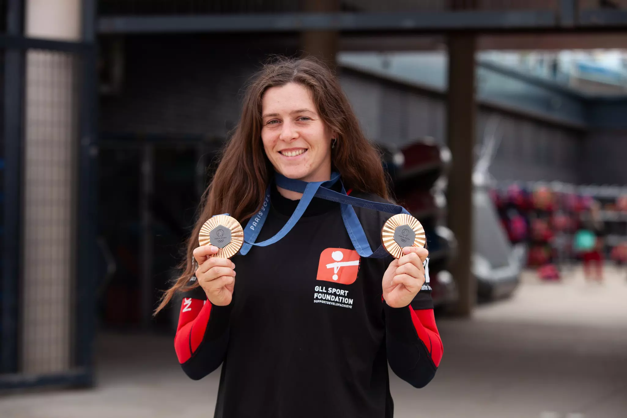 Woman displaying two gold medals.