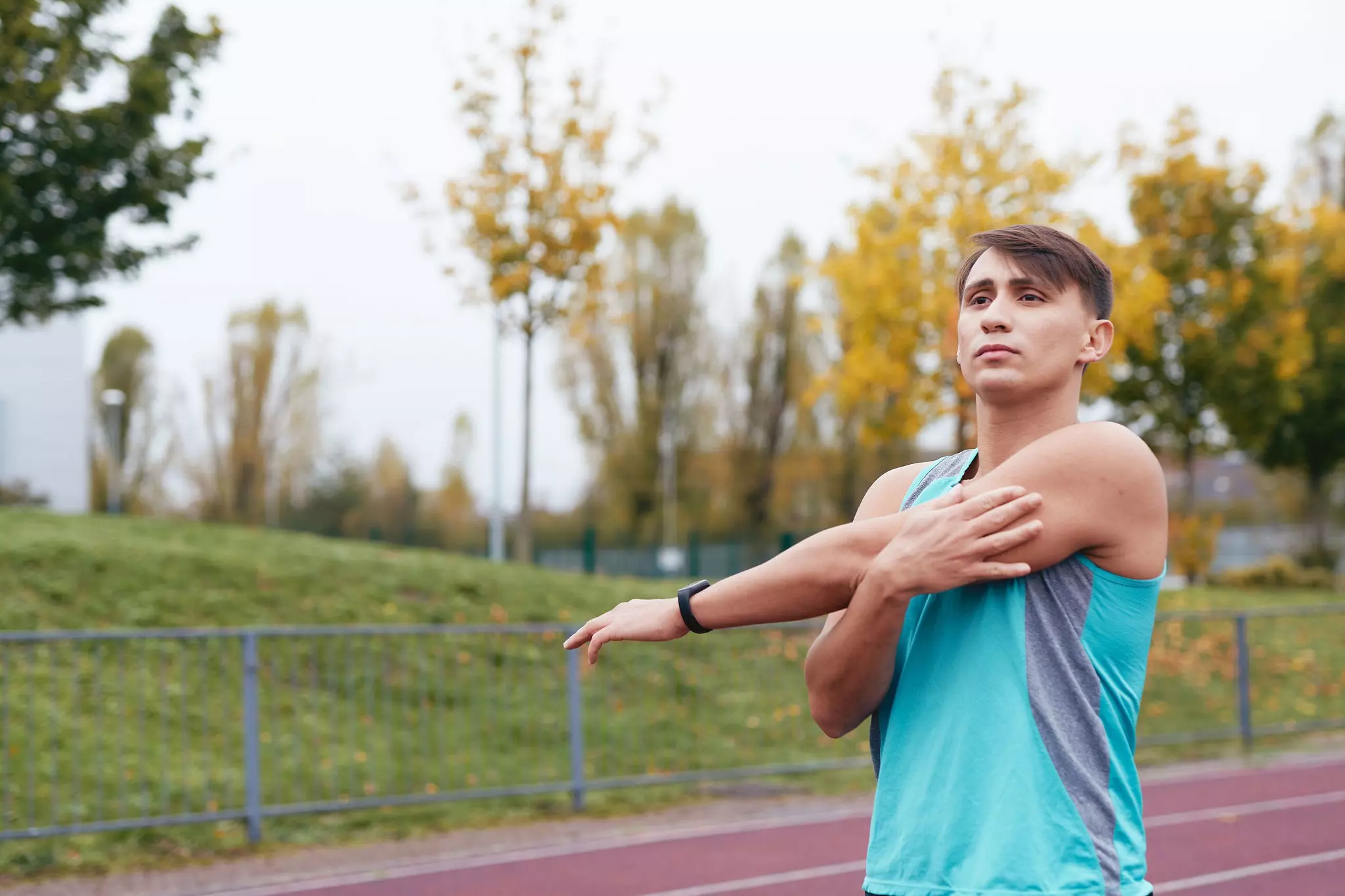 Man stretching outside on athletic track.